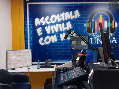 Alle spalle una porzione della parete � stata interamente colorata di blu, riproducendo un motivo a mattoncini su cui spicca in bianco il motto �Ascoltala e vivila con noi�